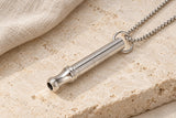 Silver-tone AUM Resonance sound meditation necklace on pale stone with linen.
