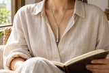 AUM Resonance silver-tone pendant worn with a natural linen shirt while reading.