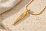 Gold-tone geometric breathing necklace with faceted pendant and matching chain on pale stone.