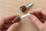 Hands replacing the white cotton core in the opened walnut Woodland Pause pendant.